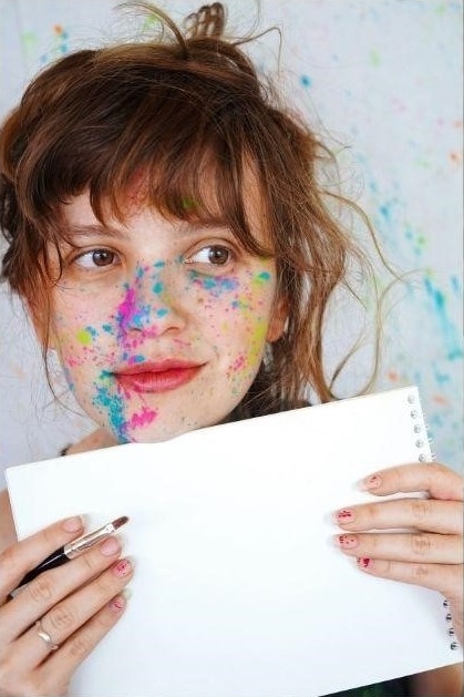 Women with paint on face holding white paper