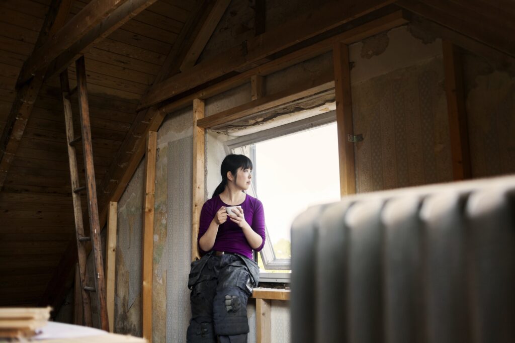 Woman during attic renovation resting by window